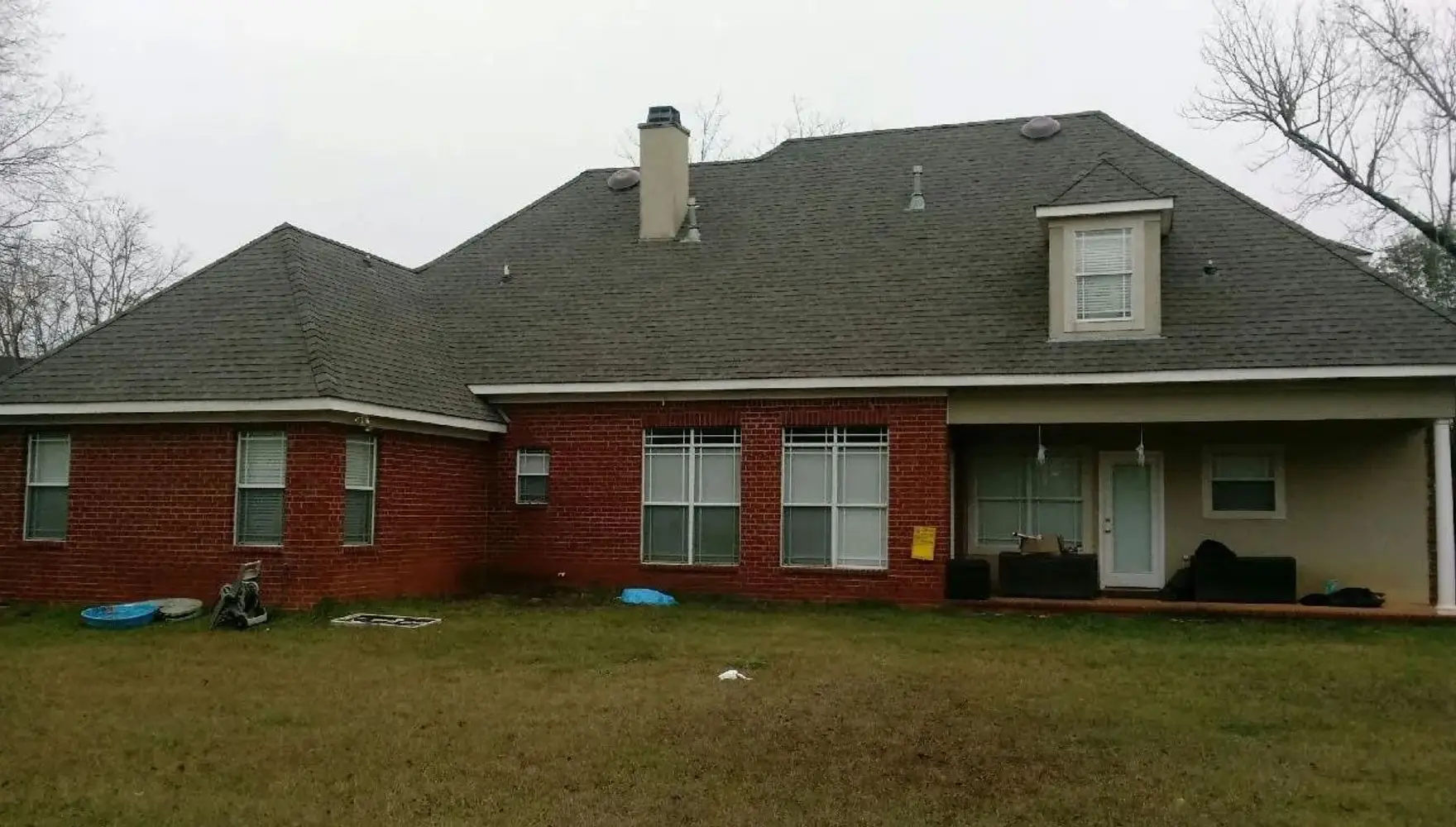 Brick home with broad low-slope roof planes, typical of flat and low-pitch roofing work.