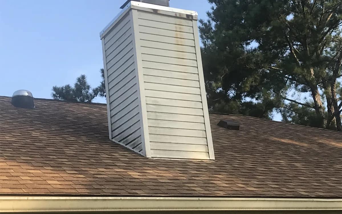 Chimney chase and new metal cap flashing on a shingle roof, photographed close on a Liberty Roofing job