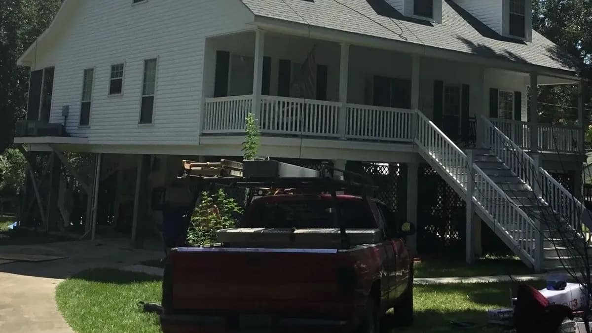 Liberty Roofing work truck parked in the driveway of an elevated coastal home with a newly installed roof