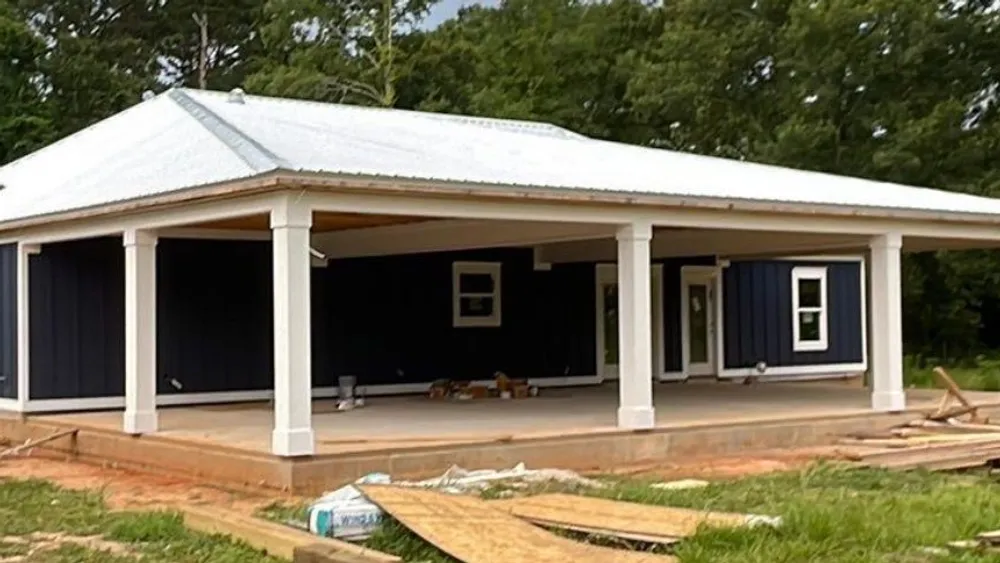 White low-slope metal roof over the wraparound porch of a new-construction Baldwin County home