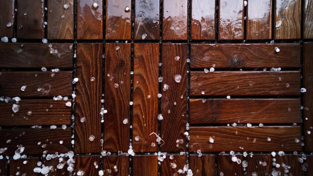 Hailstones scattered across a wet wooden deck after a storm