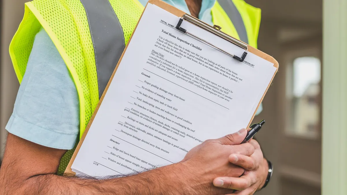 An inspector in a hi-vis vest holding a printed inspection checklist on a clipboard