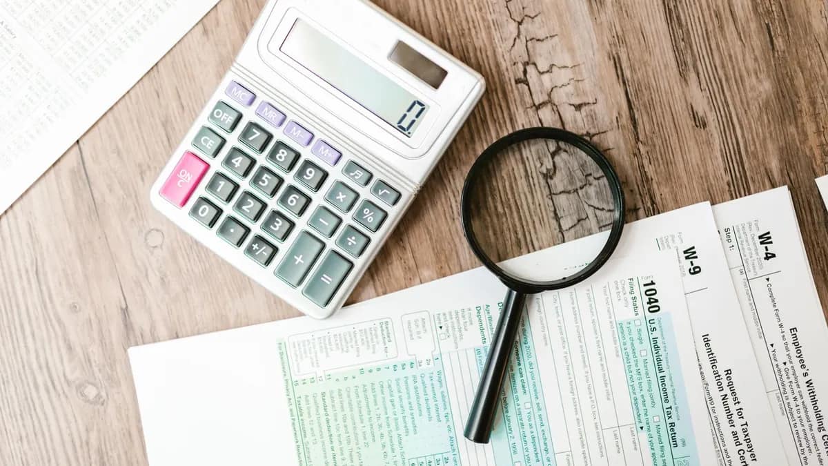 Federal tax forms spread across a table with a calculator and a magnifying glass