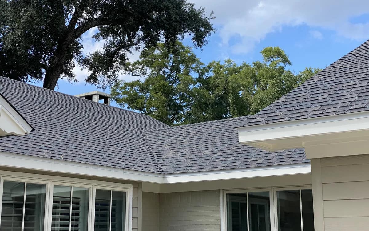 Finished gray architectural shingle roof with a hip and valley on a Baldwin County home, live oaks overhead
