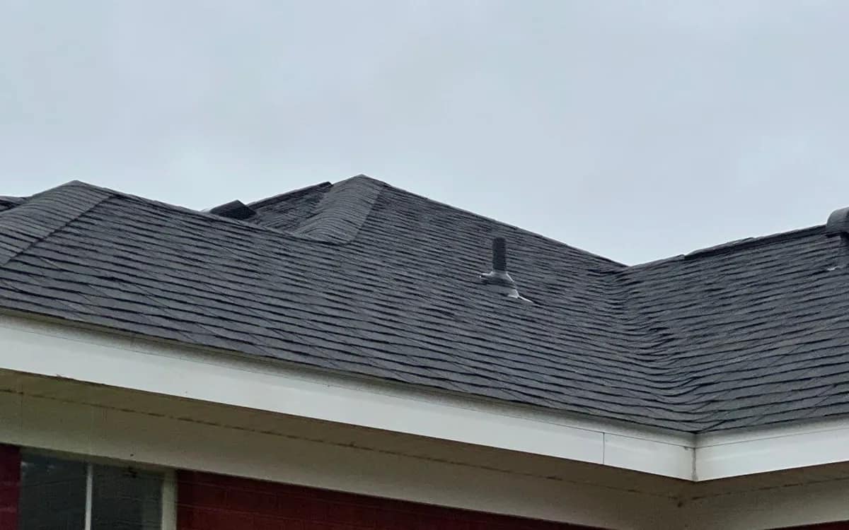 Eave, gutter line and drip edge along the perimeter of a dark shingle roof on a brick Alabama home