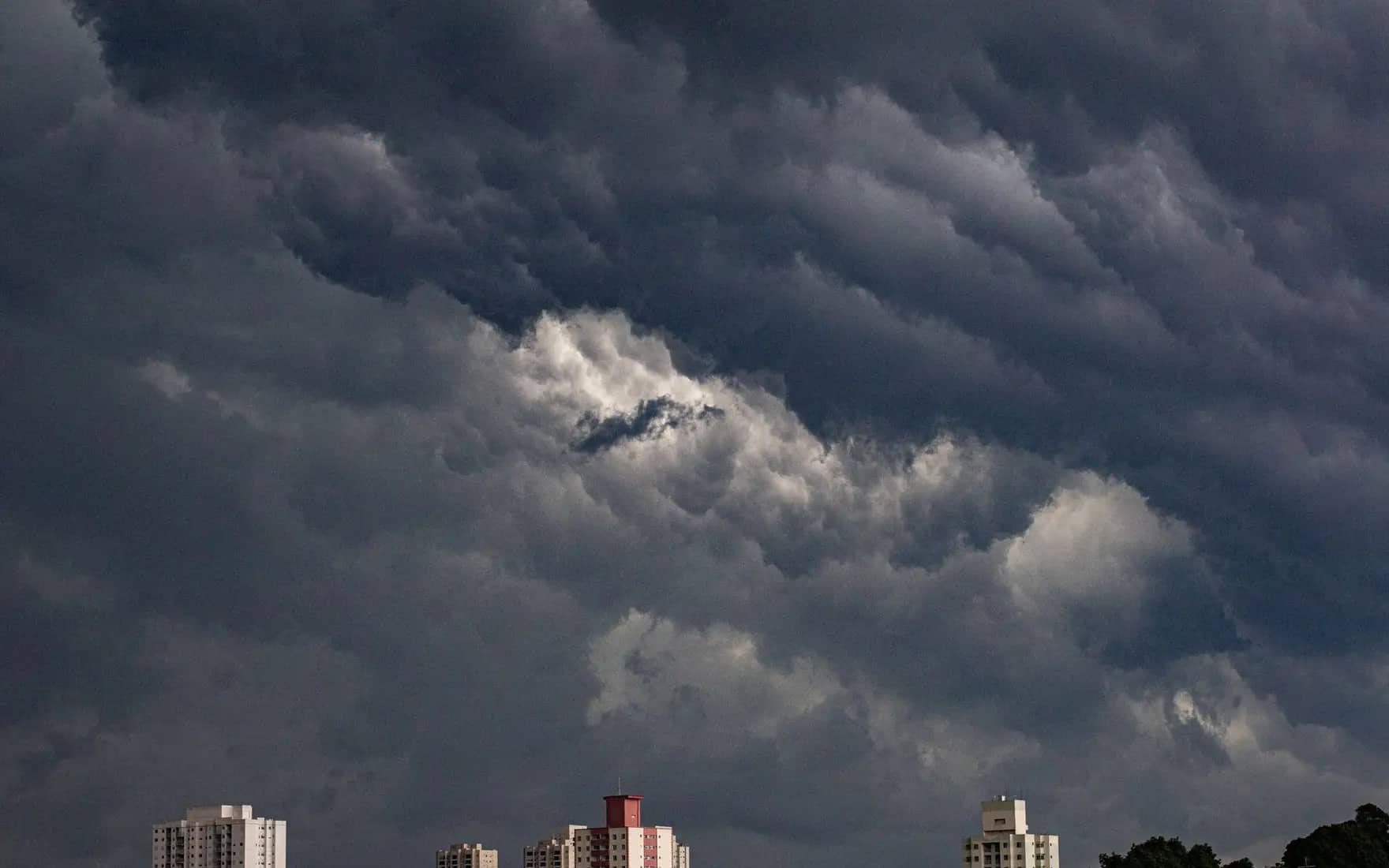Dark, dramatic storm clouds gathering over a city at dusk.